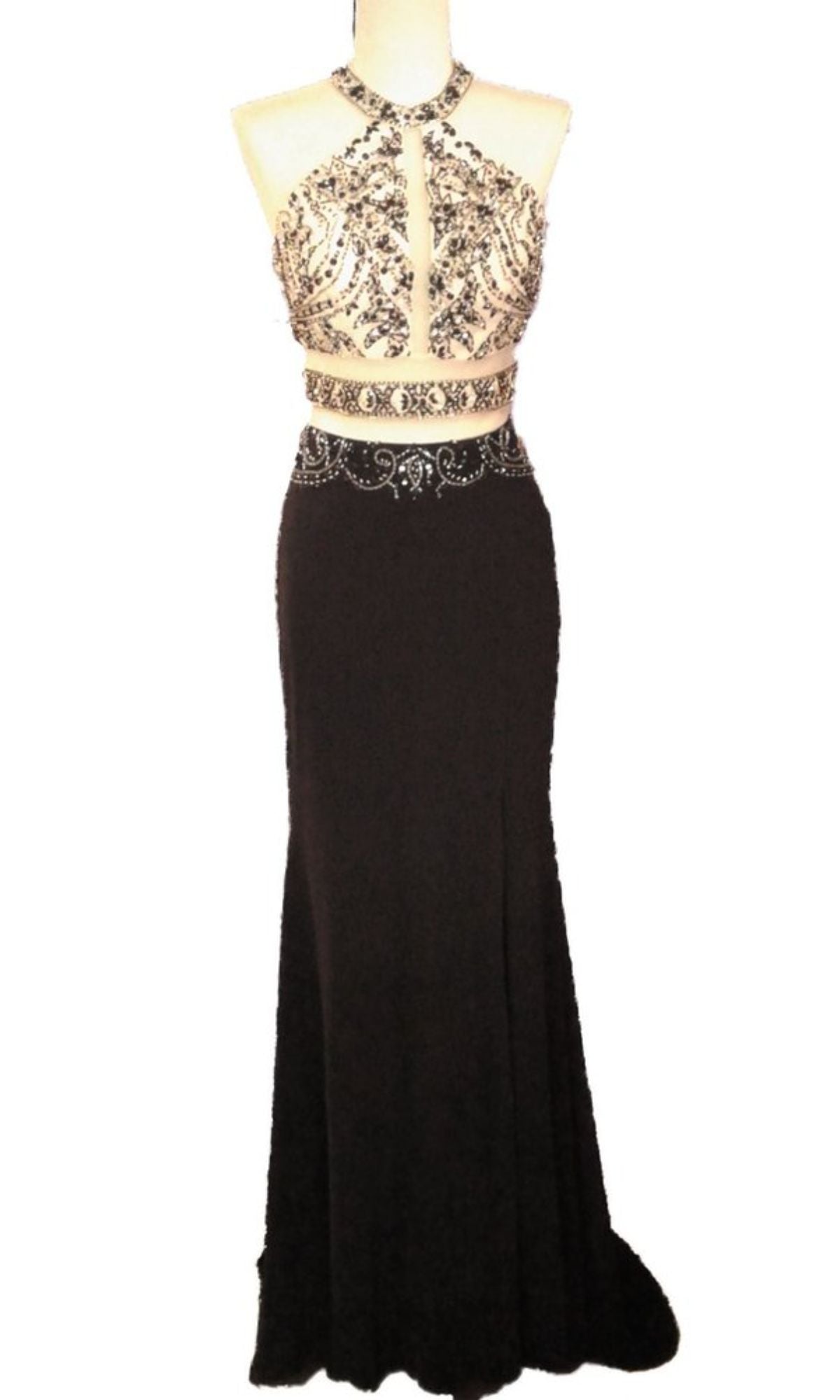 The Chicas CR7001 Faux Two-Piece Long Prom Dress features a sleeveless black design with a beaded bodice, keyhole neckline, cutout midriff, and flowing skirt, displayed on a dress form.